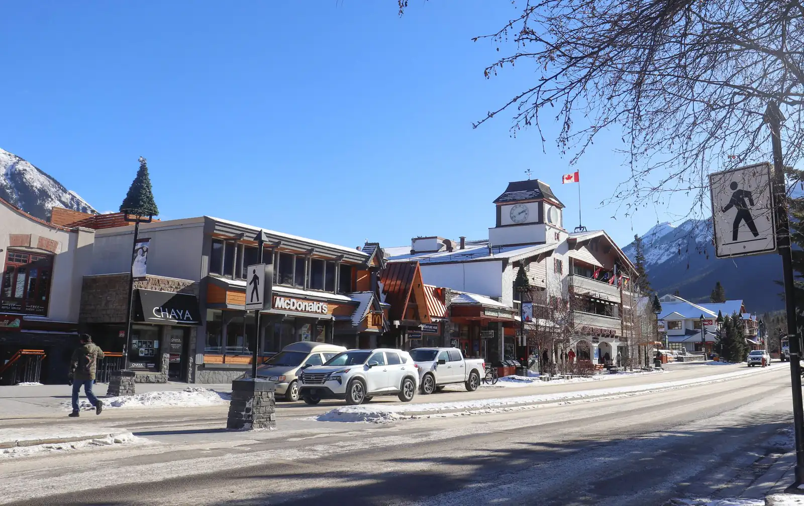 A snowy main street in Banff with mountains behind on a bright winter day