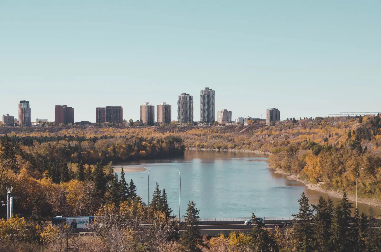 Autumn colours around a lake in Edmonton’s river valley with towers on the skyline